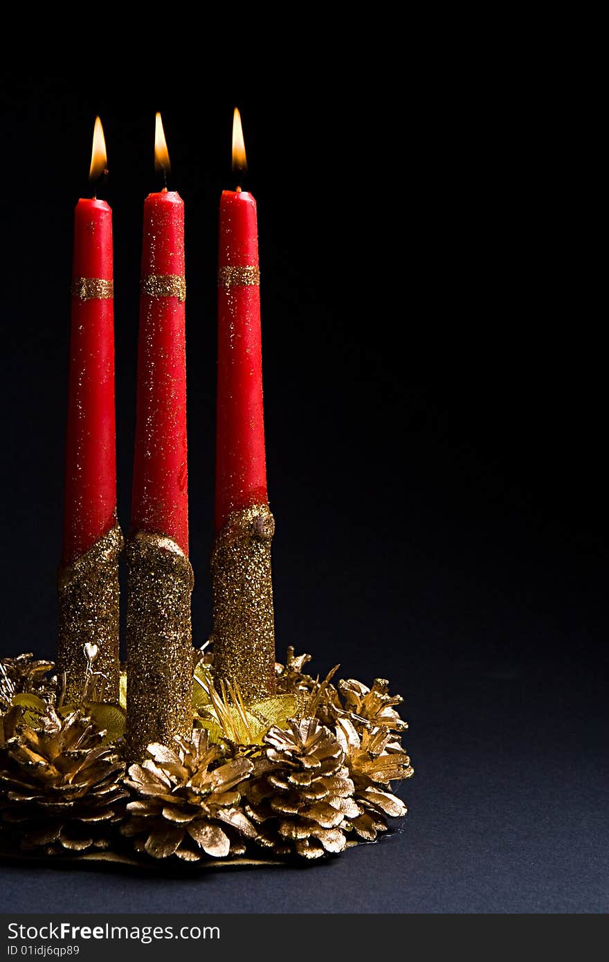 Beautiful red candles in a candlestick from gold cones against a dark background. Beautiful red candles in a candlestick from gold cones against a dark background