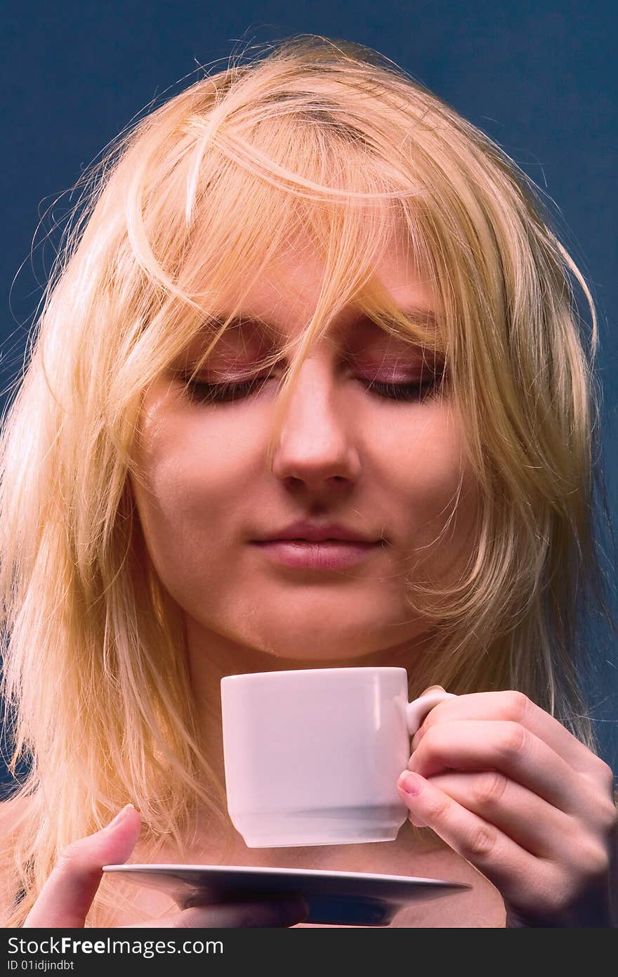 Young beautiful girl a blonde enjoys the divine aroma of coffee. Young beautiful girl a blonde enjoys the divine aroma of coffee