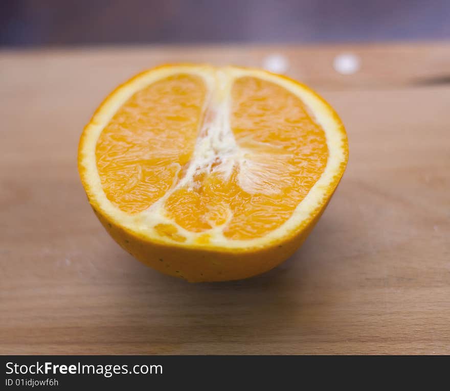 Half-orange lies on a wooden board, small depth of sharpness