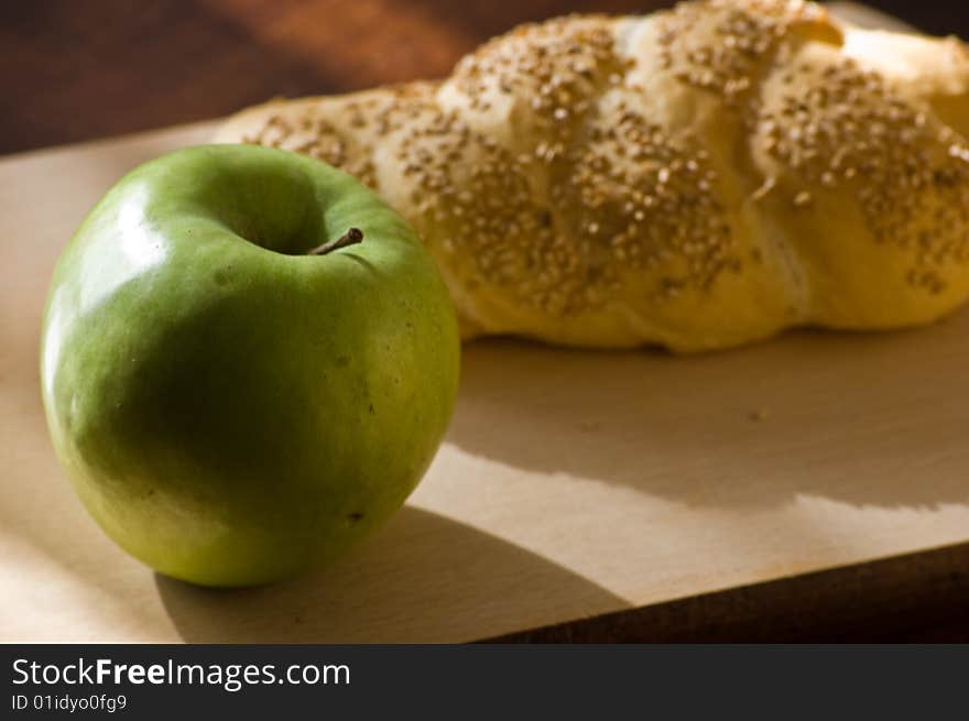 A bread loaf on a wooden table, with a green apple. A bread loaf on a wooden table, with a green apple