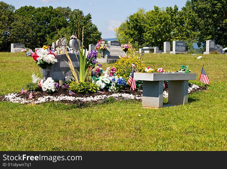 Cemetery with focus on a dual grave plot with a lot of flowers and ornaments. Cemetery with focus on a dual grave plot with a lot of flowers and ornaments.