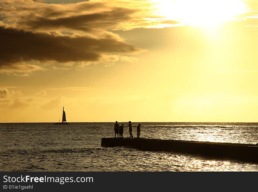 Sunset on pier, silhouette of family and sail boat