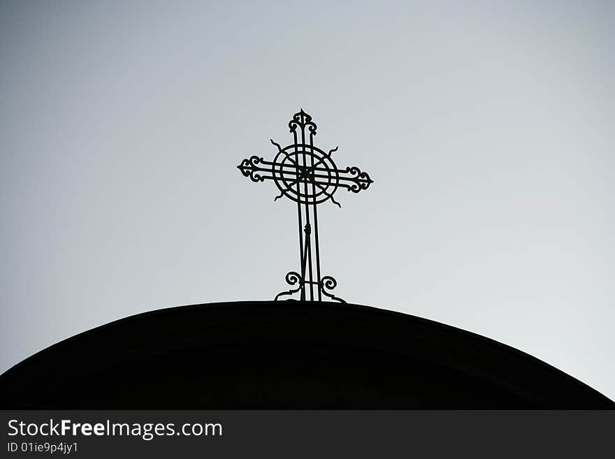 A shilouette of a cast iron cross on a church dome against a dull sky. A shilouette of a cast iron cross on a church dome against a dull sky