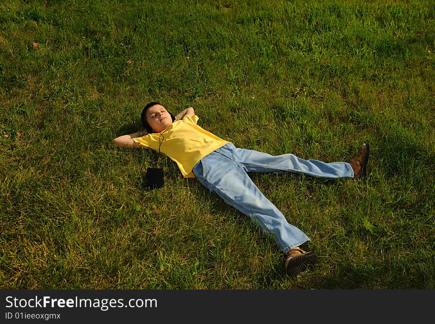 The young boy lying on the grass and listening to music. The young boy lying on the grass and listening to music