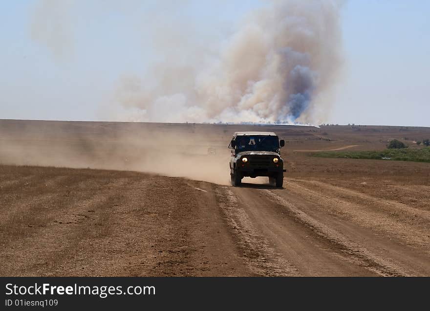 Military car on desert road escapes from fire. Military car on desert road escapes from fire