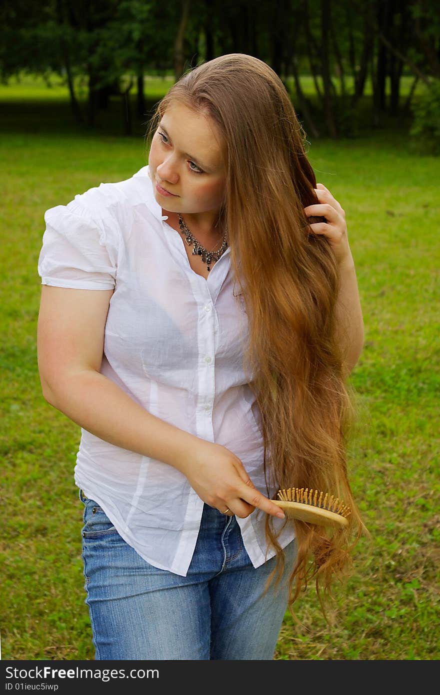 Blond girl styling her long hair. Blond girl styling her long hair