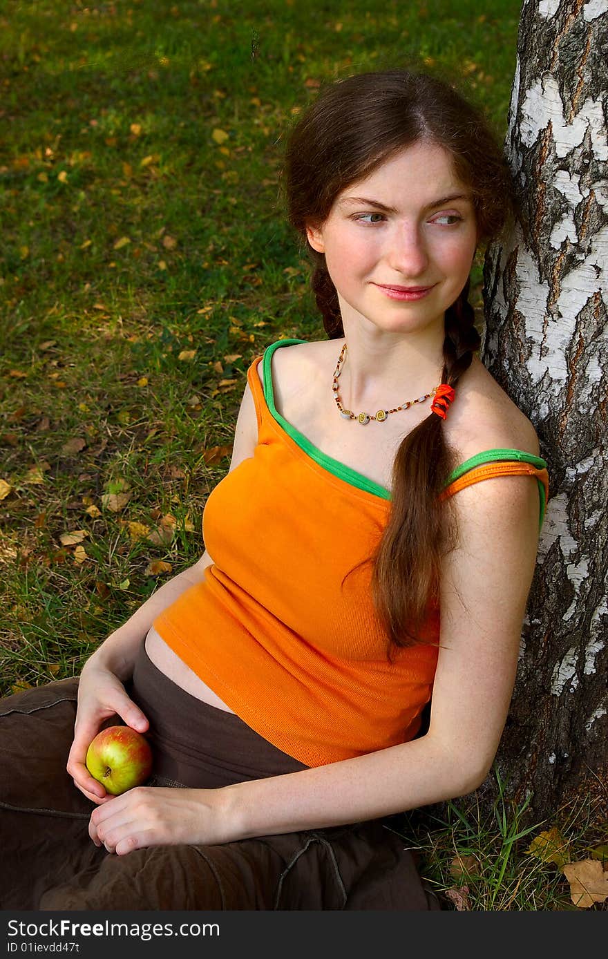 Pregnant girl with an apple under a tree