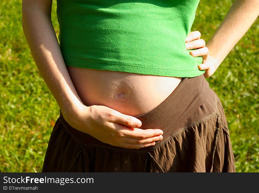 Pregnant girl holding her tummy with a hand