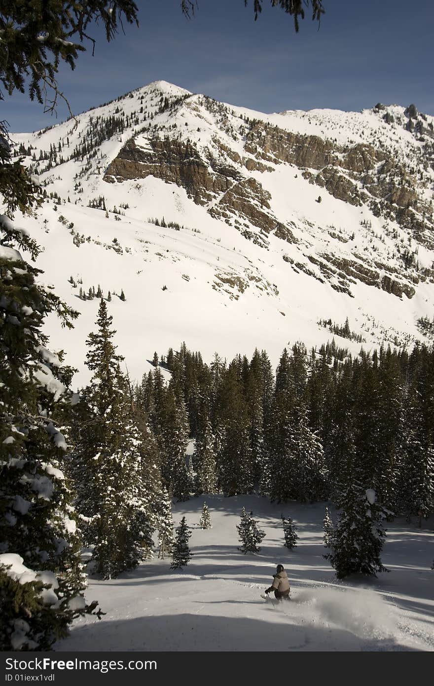 A lone Powder skier under a tall mountain peak