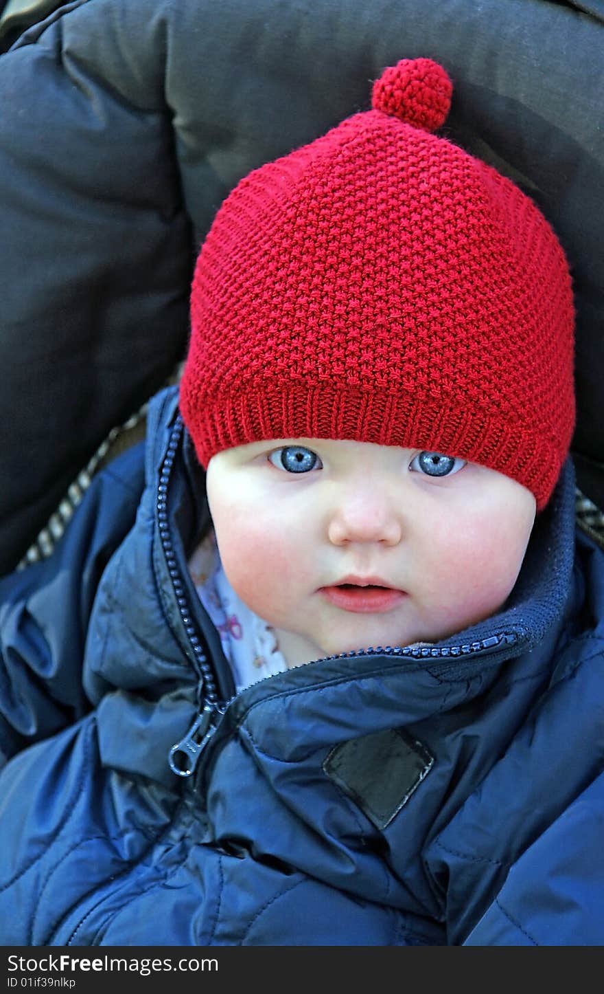 An infant girl with bright blue eyes is bundled up in her stroller outdoors in the fresh air. An infant girl with bright blue eyes is bundled up in her stroller outdoors in the fresh air.