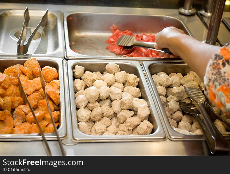 Lunch or dinner meal at a japanese restaurant. customer picking raw food on buffet to be cooked (grilled or boiled). Lunch or dinner meal at a japanese restaurant. customer picking raw food on buffet to be cooked (grilled or boiled)