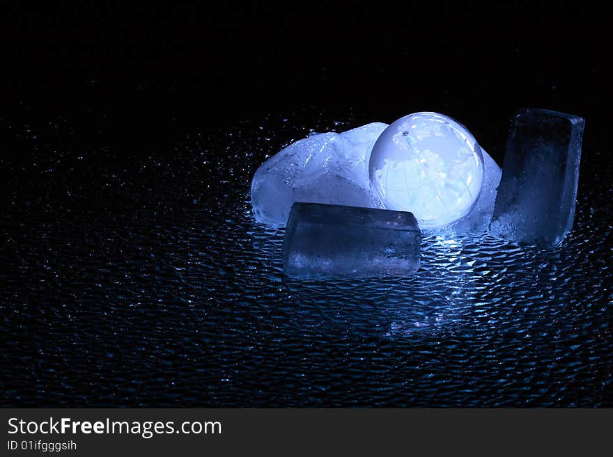 Dark background with glassy globe inside block of ice. Dark background with glassy globe inside block of ice