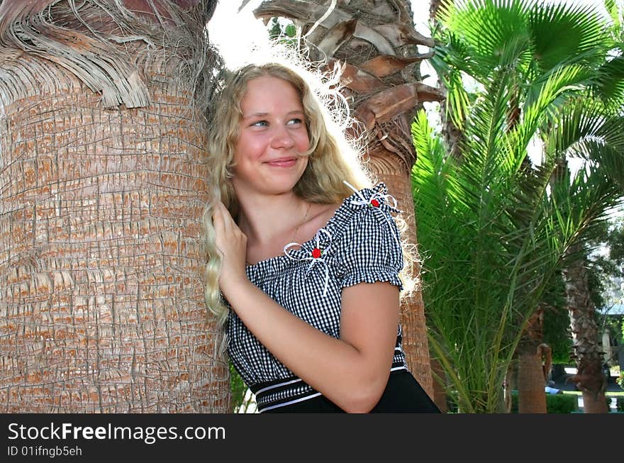 Pretty blond girl at the palm tree.