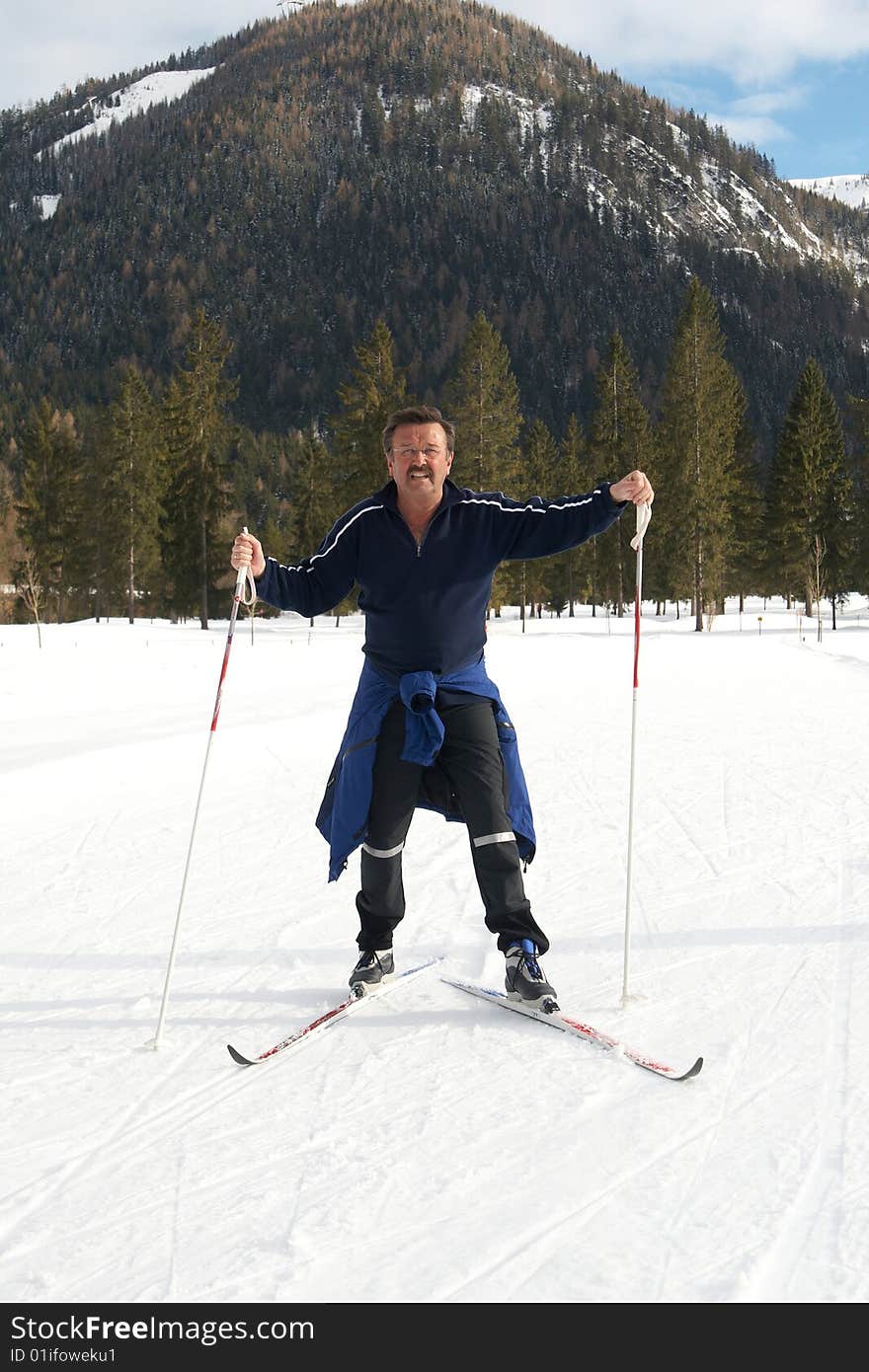 A senior man outdoor doing cross country skiing in a winter setting. A senior man outdoor doing cross country skiing in a winter setting.