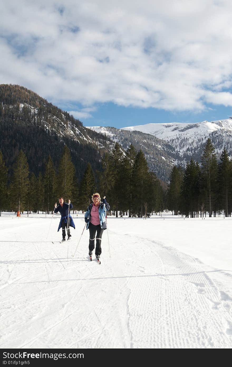 A senior couple outdoor doing cross country skiing in a winter setting. A senior couple outdoor doing cross country skiing in a winter setting.