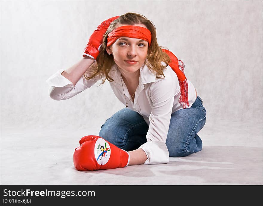 Girl is sitting with red boxing gloves, bending forward,  isolated on a white background. Girl is sitting with red boxing gloves, bending forward,  isolated on a white background