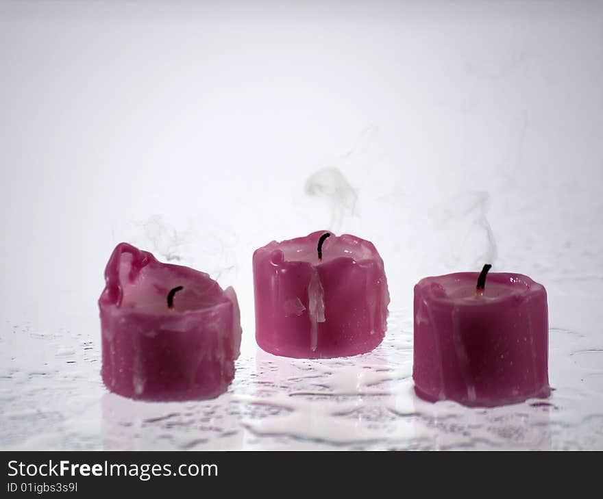 Candles, extinct standing on a wet surface that reflects light