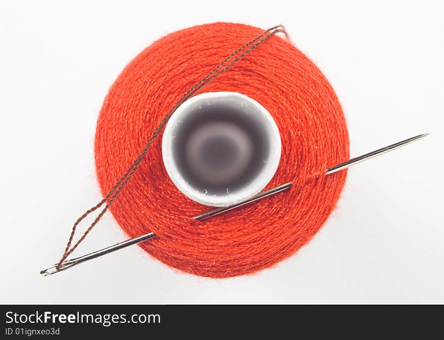 Close up of a red sewing spool with a needle