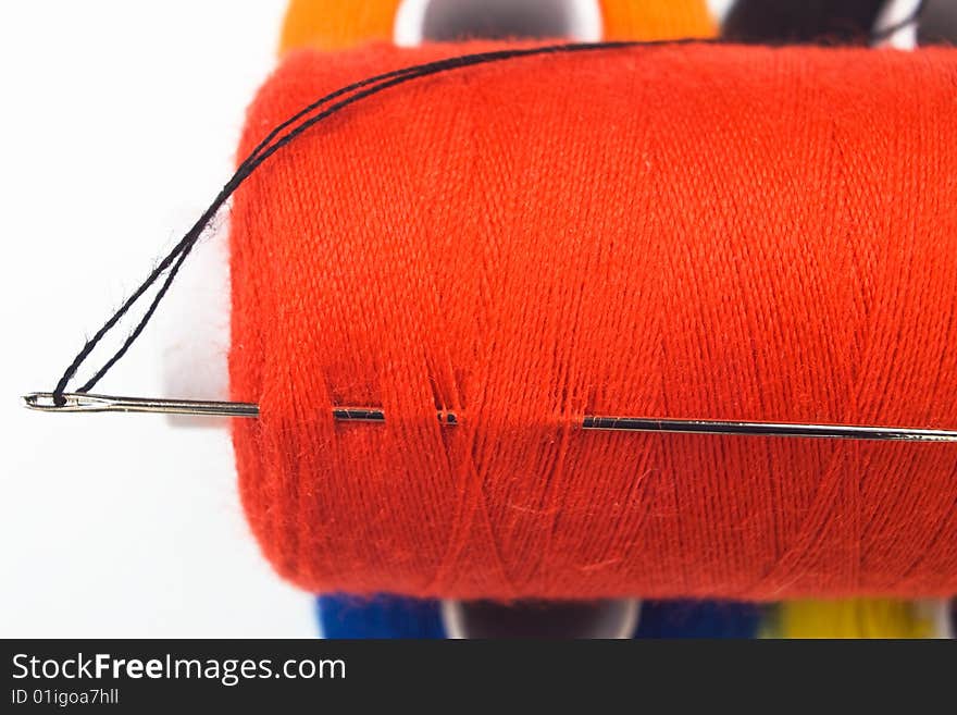 Close up of a red sewing spool with a needle