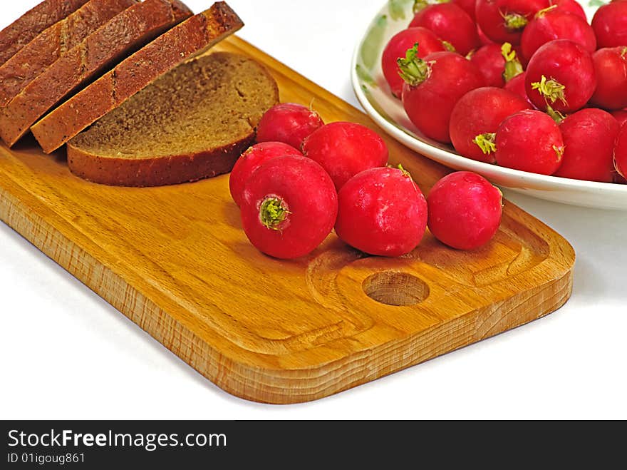 Garden radish and brown bread on wooden plate