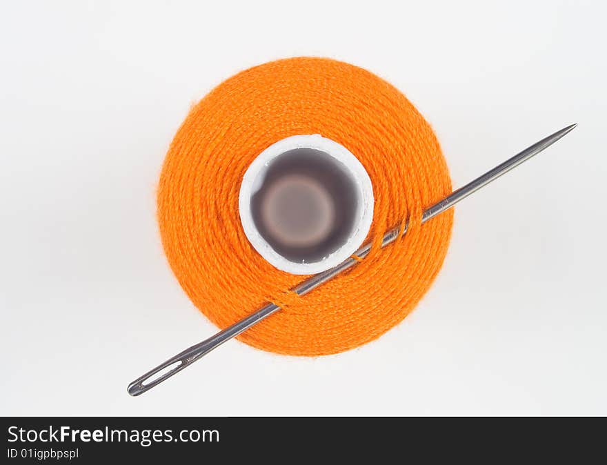 Close up of a orange sewing spool with needle