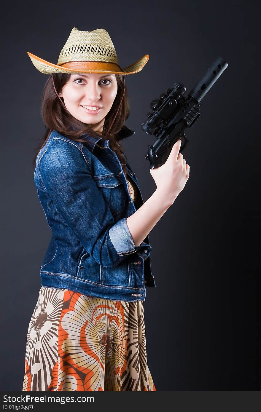 Girl in a cowboy's hat with the big pistol against a dark background. Girl in a cowboy's hat with the big pistol against a dark background