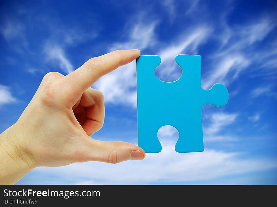 Puzzle in hand isolated on sky background