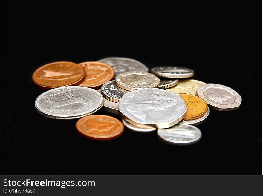 Assorted coins scattered on a black background