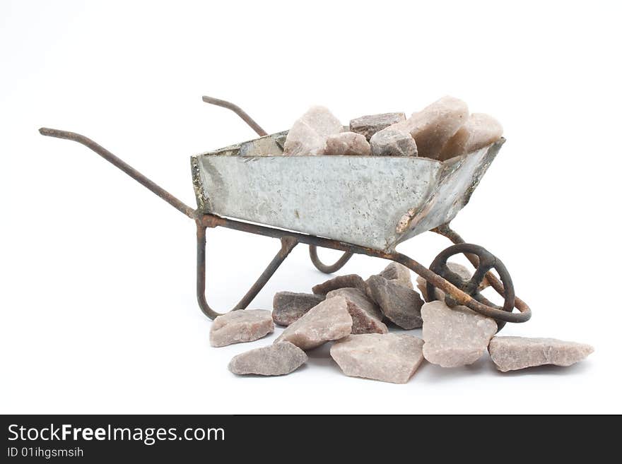 This is a wheelbarrow with rocks in it and around it. This is a wheelbarrow with rocks in it and around it