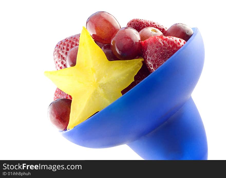 Colorful blue bowl of mixed fruit with starfruit, diagonal, isolated on white background with copy space. Colorful blue bowl of mixed fruit with starfruit, diagonal, isolated on white background with copy space