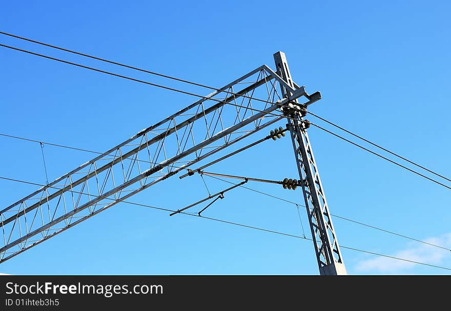 Railway pylons of the high tension line with blue sky