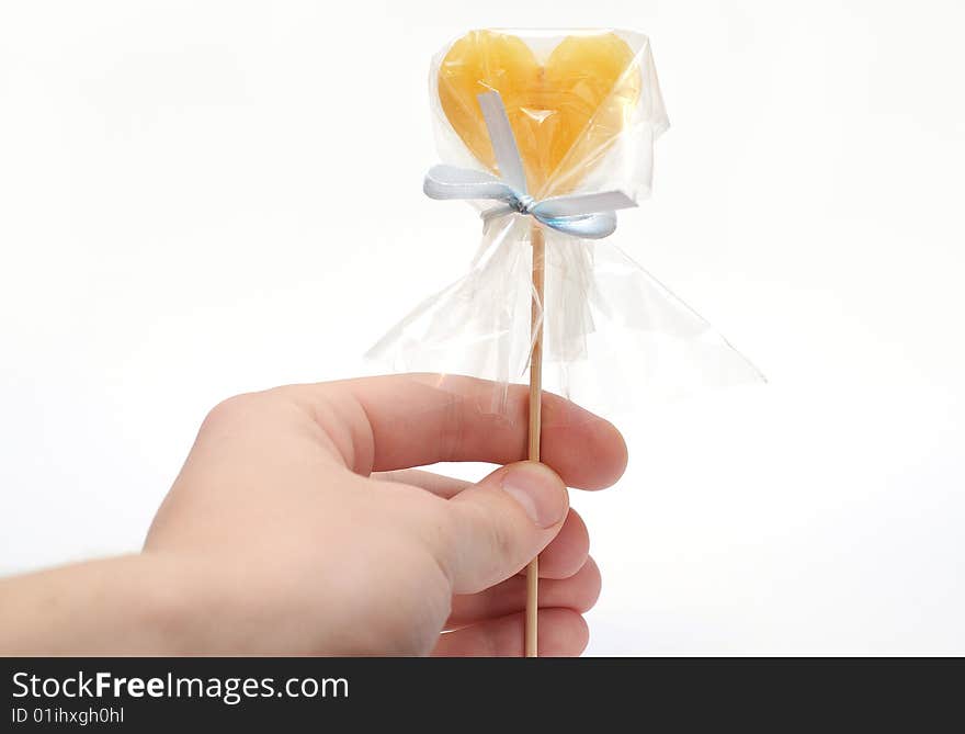 Hand with caramel candy on stick as a Valentine treat on white background isolated. Hand with caramel candy on stick as a Valentine treat on white background isolated