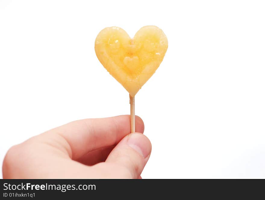 Hand with caramel candy on stick as a Valentine treat on white background isolated. Hand with caramel candy on stick as a Valentine treat on white background isolated