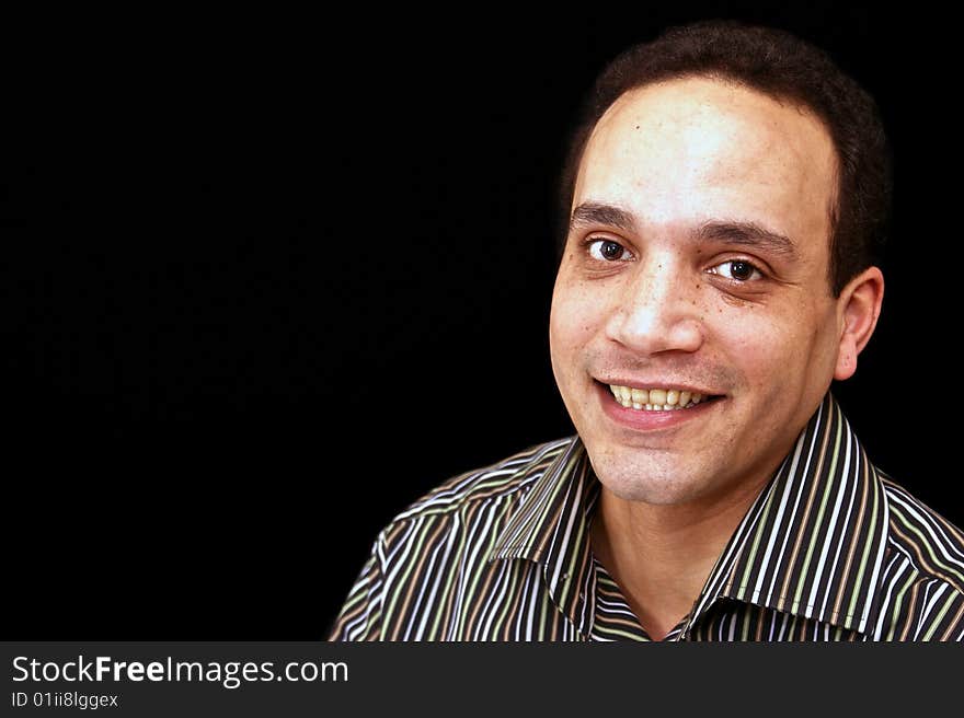 Happy african american male wearing striped shirt against black background with big toothy grin. Happy african american male wearing striped shirt against black background with big toothy grin