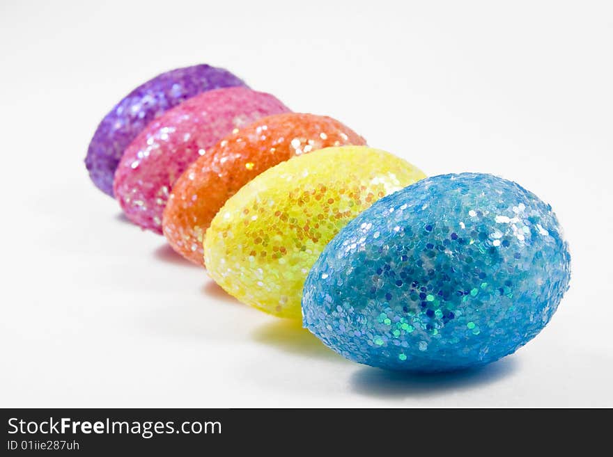 Five colorful eggs isolated in white arranged in a row shot from the side. Five colorful eggs isolated in white arranged in a row shot from the side