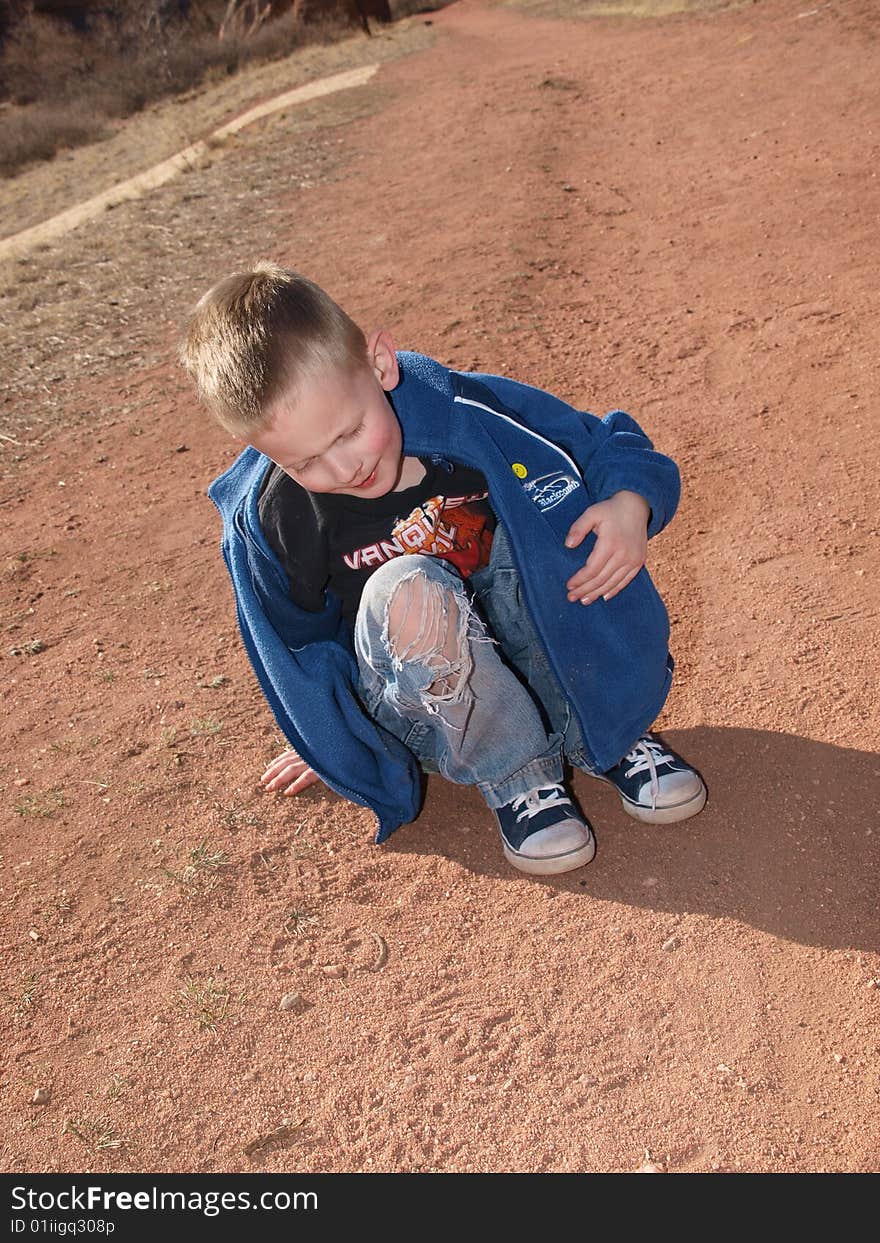 A color image of a youn boy sitting in the red dirt. A color image of a youn boy sitting in the red dirt.