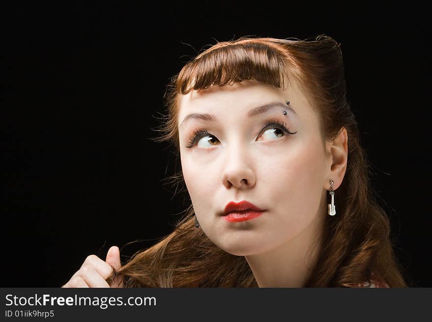 Pretty pensive retro-style woman touching her hair, looking up over dark background