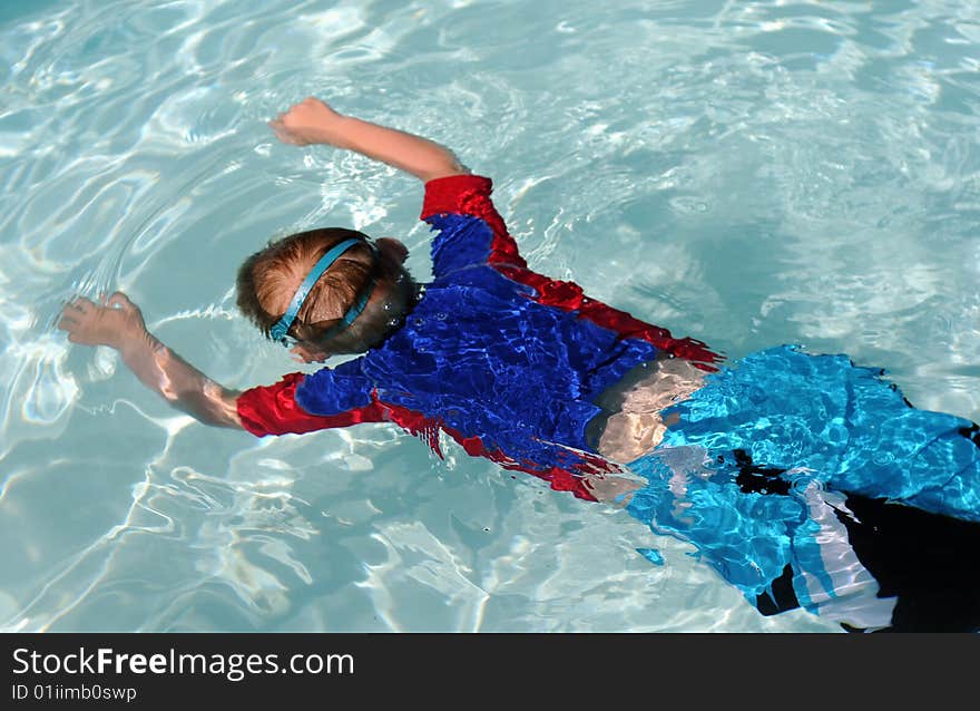 Boy floating in a pool with goggles. Boy floating in a pool with goggles