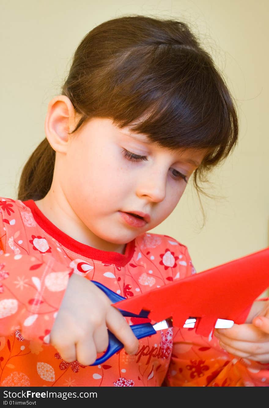 5 years old girl cutting red paper with scissors. 5 years old girl cutting red paper with scissors