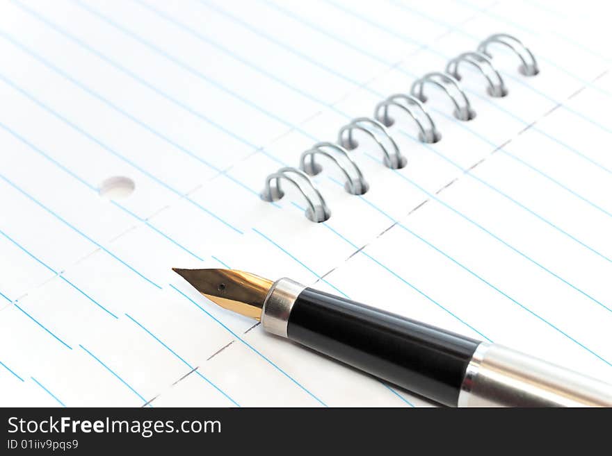 A gold-nibbed pen on a spiral-bound notepad. A gold-nibbed pen on a spiral-bound notepad