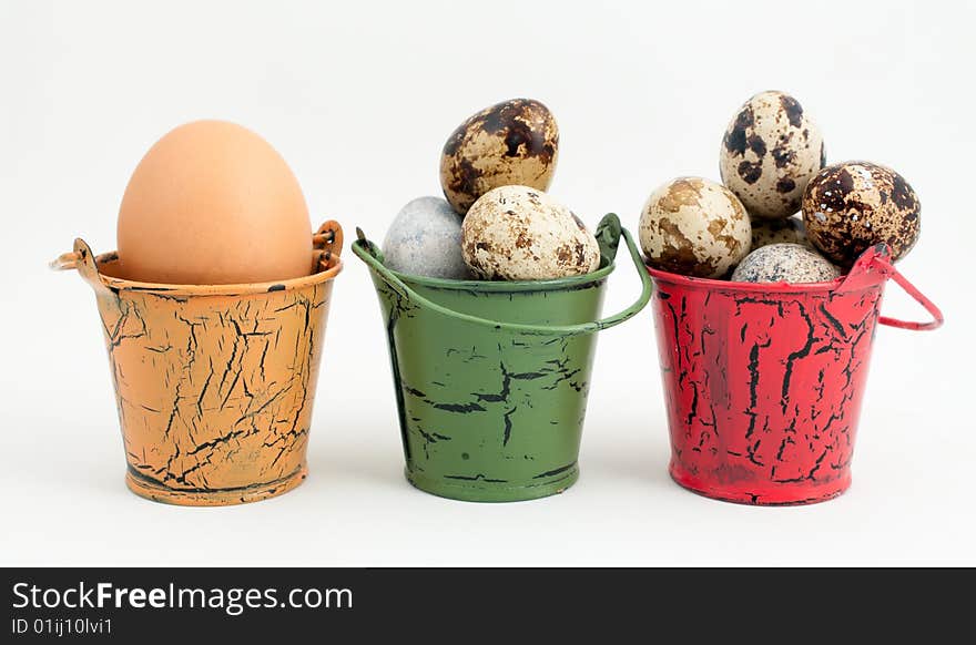 A row of toy buckets each with eggs on white background. A row of toy buckets each with eggs on white background