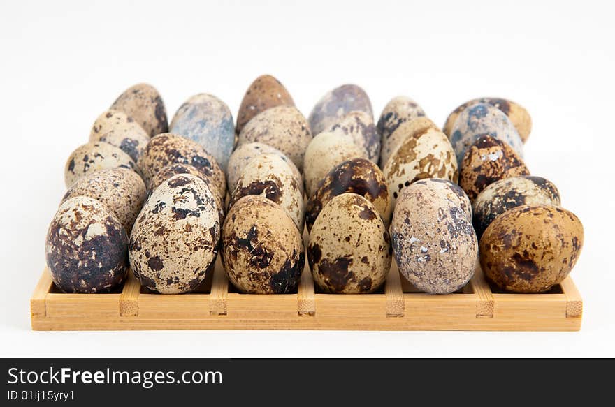 Quail eggs placed on a square wooden grid on white background. Quail eggs placed on a square wooden grid on white background