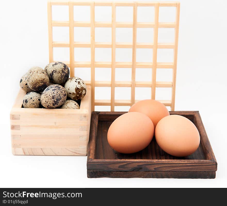 Zen inspired arrangement of quail and chicken eggs in wooden containers with square wooden grid in background. Zen inspired arrangement of quail and chicken eggs in wooden containers with square wooden grid in background