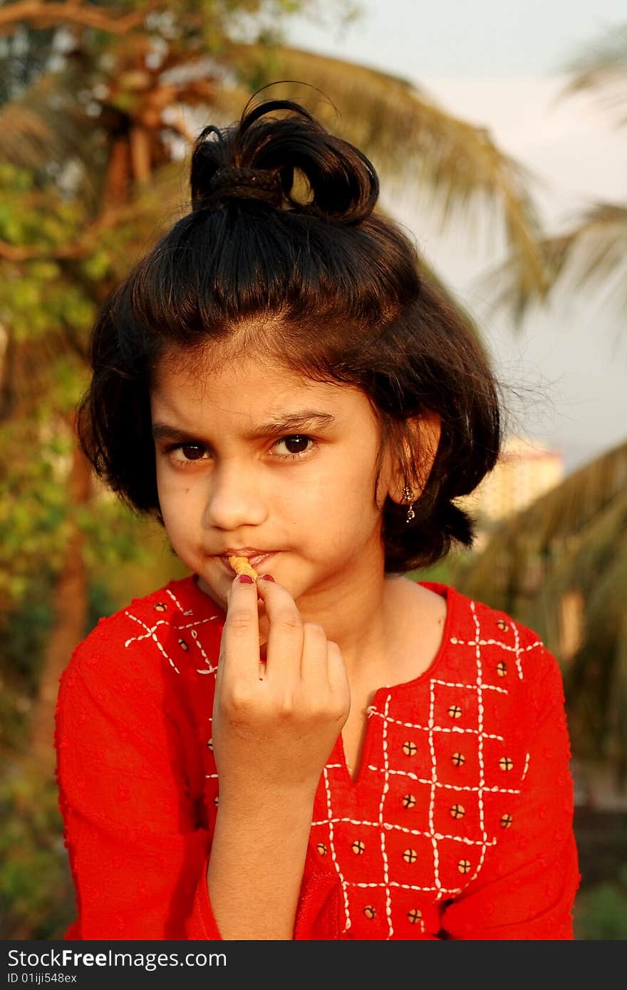 A nice and beautiful Indian girl watching the onlooker while eating something. A nice and beautiful Indian girl watching the onlooker while eating something.