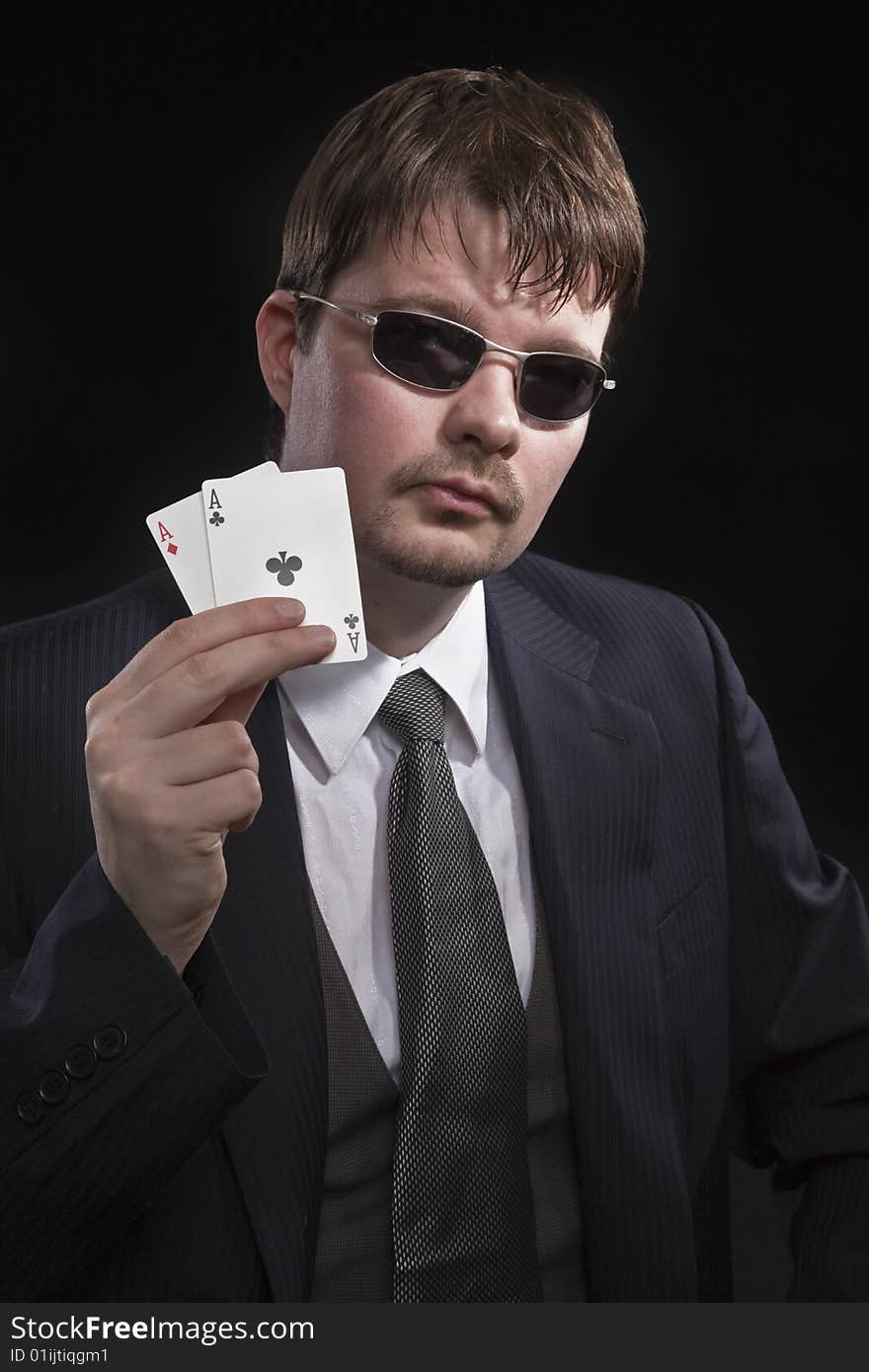 Man in suit with sun glasses playing poker on green table. Chips and cards on the table. Man in suit with sun glasses playing poker on green table. Chips and cards on the table.