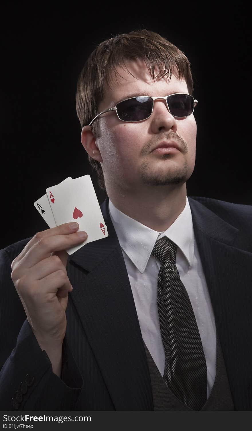 Man in suit with sun glasses playing poker on green table. Chips and cards on the table. Man in suit with sun glasses playing poker on green table. Chips and cards on the table.