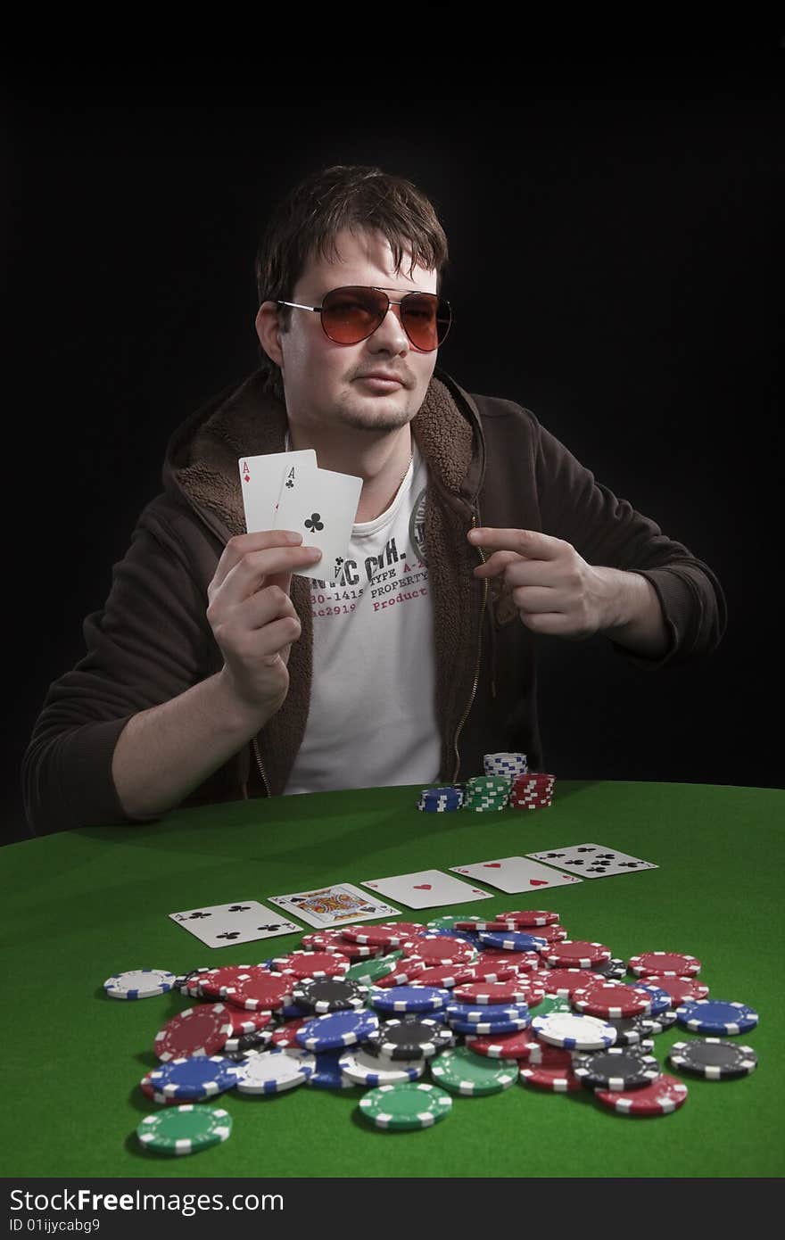 Man with sun glasses playing poker on green table. Chips and cards on the table. Man with sun glasses playing poker on green table. Chips and cards on the table.