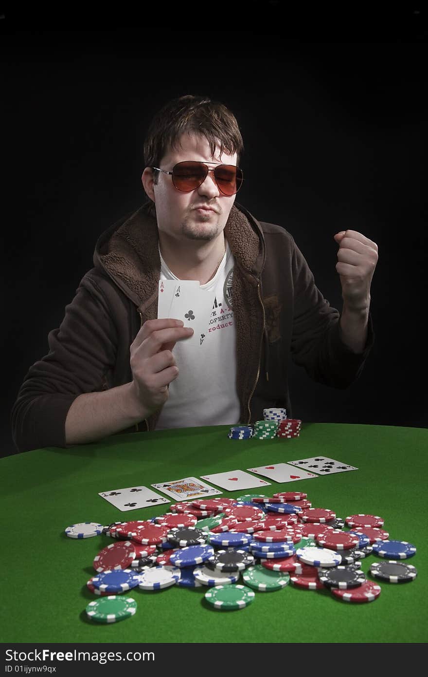 Man with sun glasses playing poker on green table. Chips and cards on the table. Man with sun glasses playing poker on green table. Chips and cards on the table.