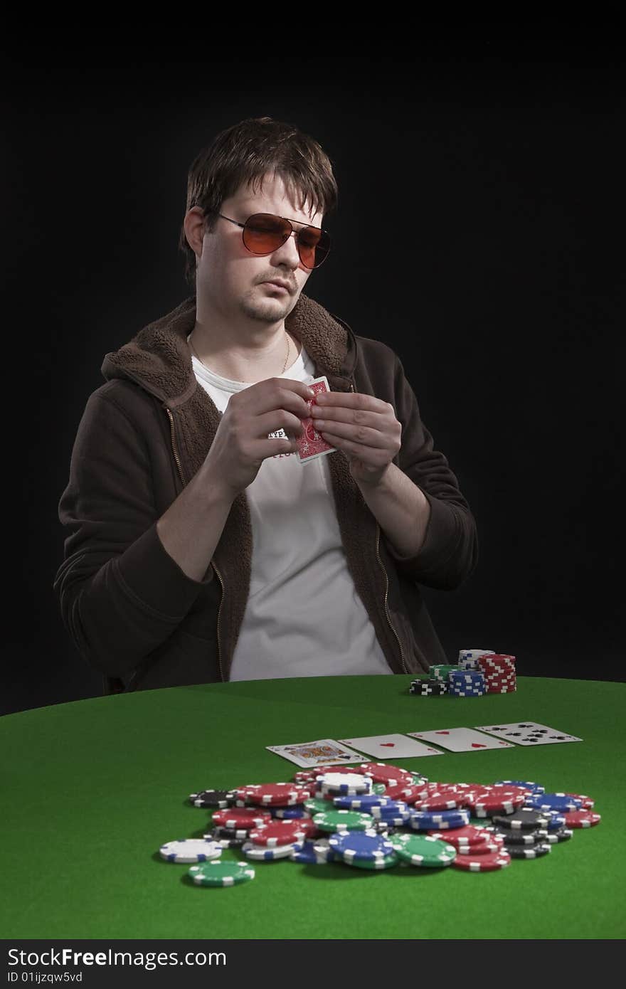 Man with sun glasses playing poker on green table. Chips and cards on the table. Man with sun glasses playing poker on green table. Chips and cards on the table.