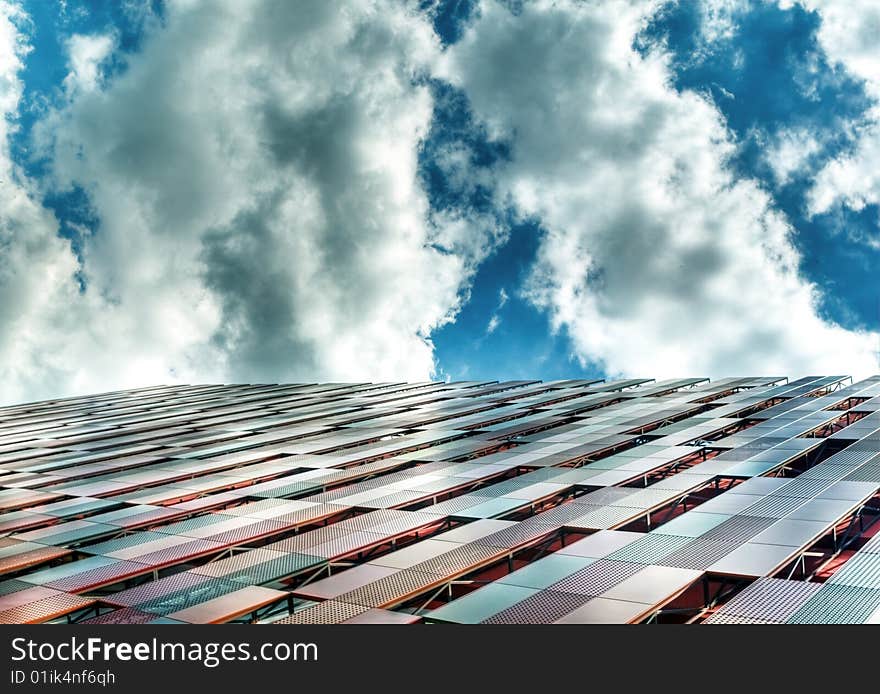 Building with interesting panel structure against a bright blue sky with interesting clouds formation. Building with interesting panel structure against a bright blue sky with interesting clouds formation